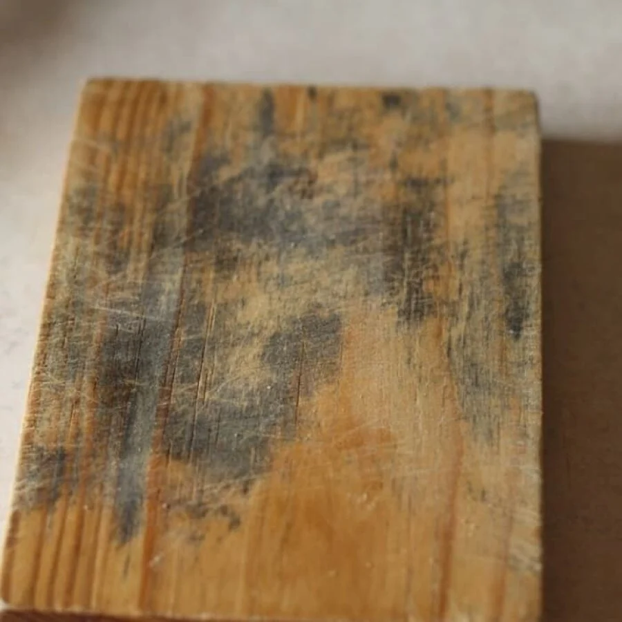 Worn wooden cutting board with dark stains in the grain